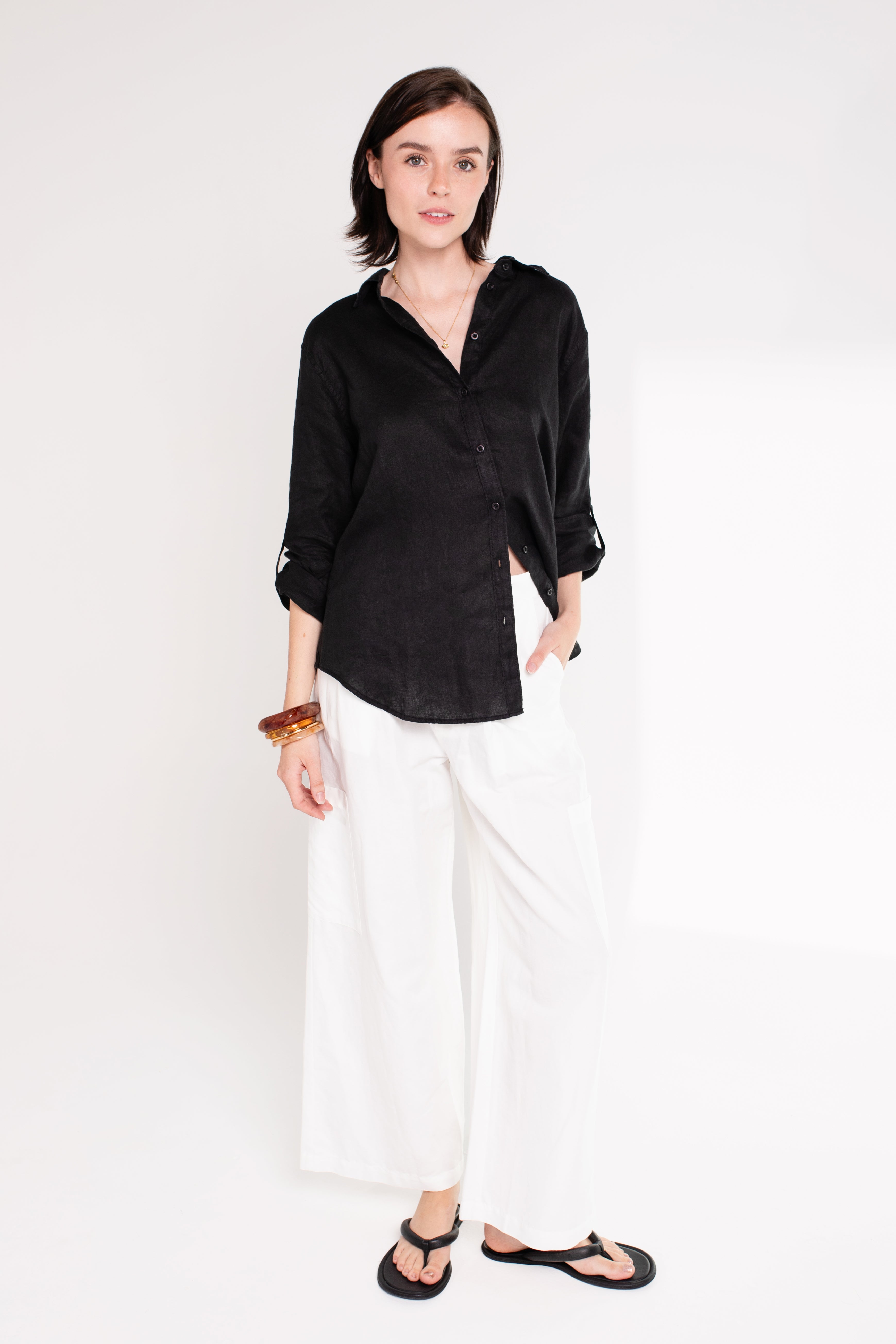 Model wearing Hut Clothing Black Embroidered Palm Boyfriend Linen Shirt made from organic Belgian linen and white pants
