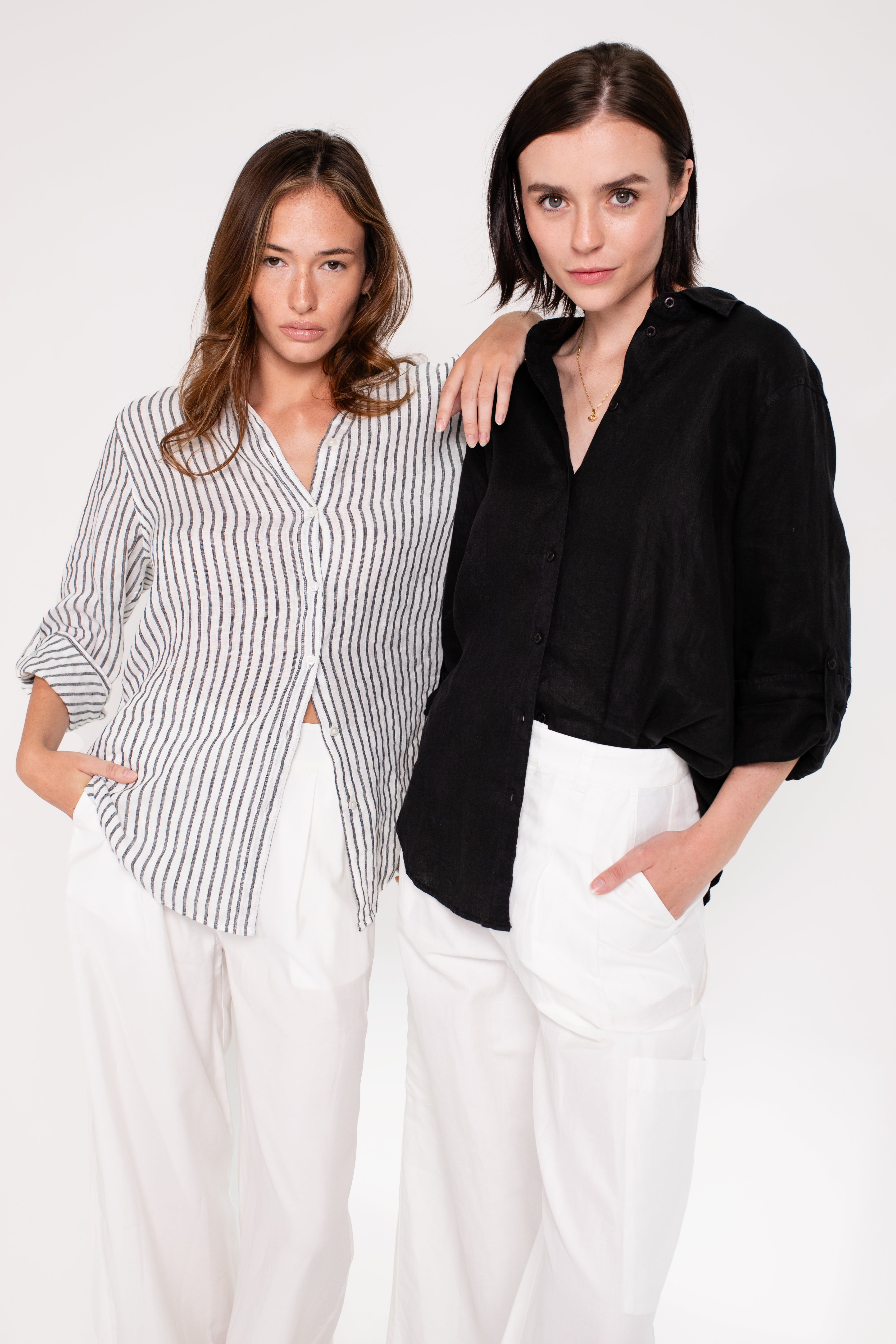 two models, one wearing Hut Black Embroidered Palm Boyfriend Linen Shirt and the other wearing a hut clothing black and white stripe boyfriend linen shirt