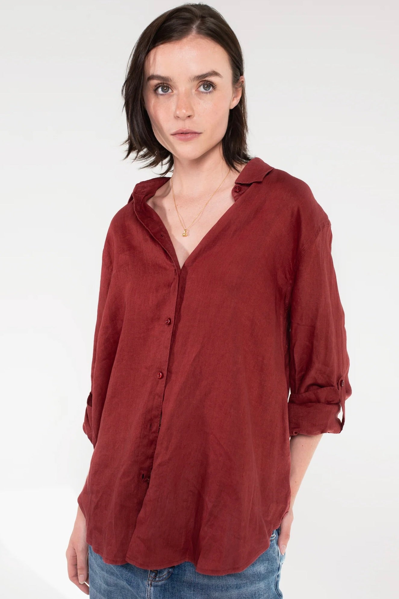 Woman wearing a Hut Burgundy Linen Boyfriend shirt with rolled-up sleeves on a white background