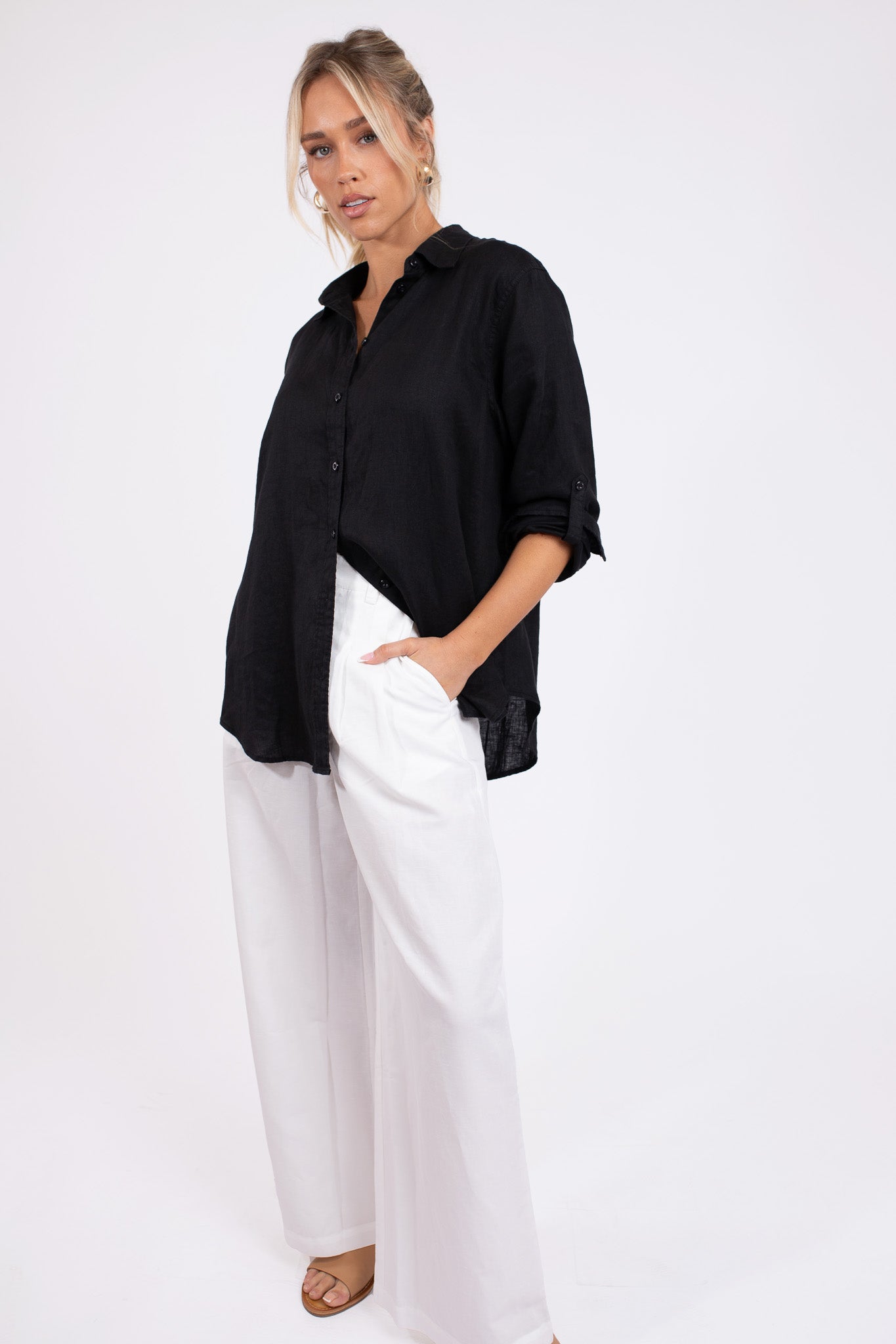 Model wearing a Hut Clothing Black No Pocket Boyfriend Linen Shirt with white linen pants standing against a white background