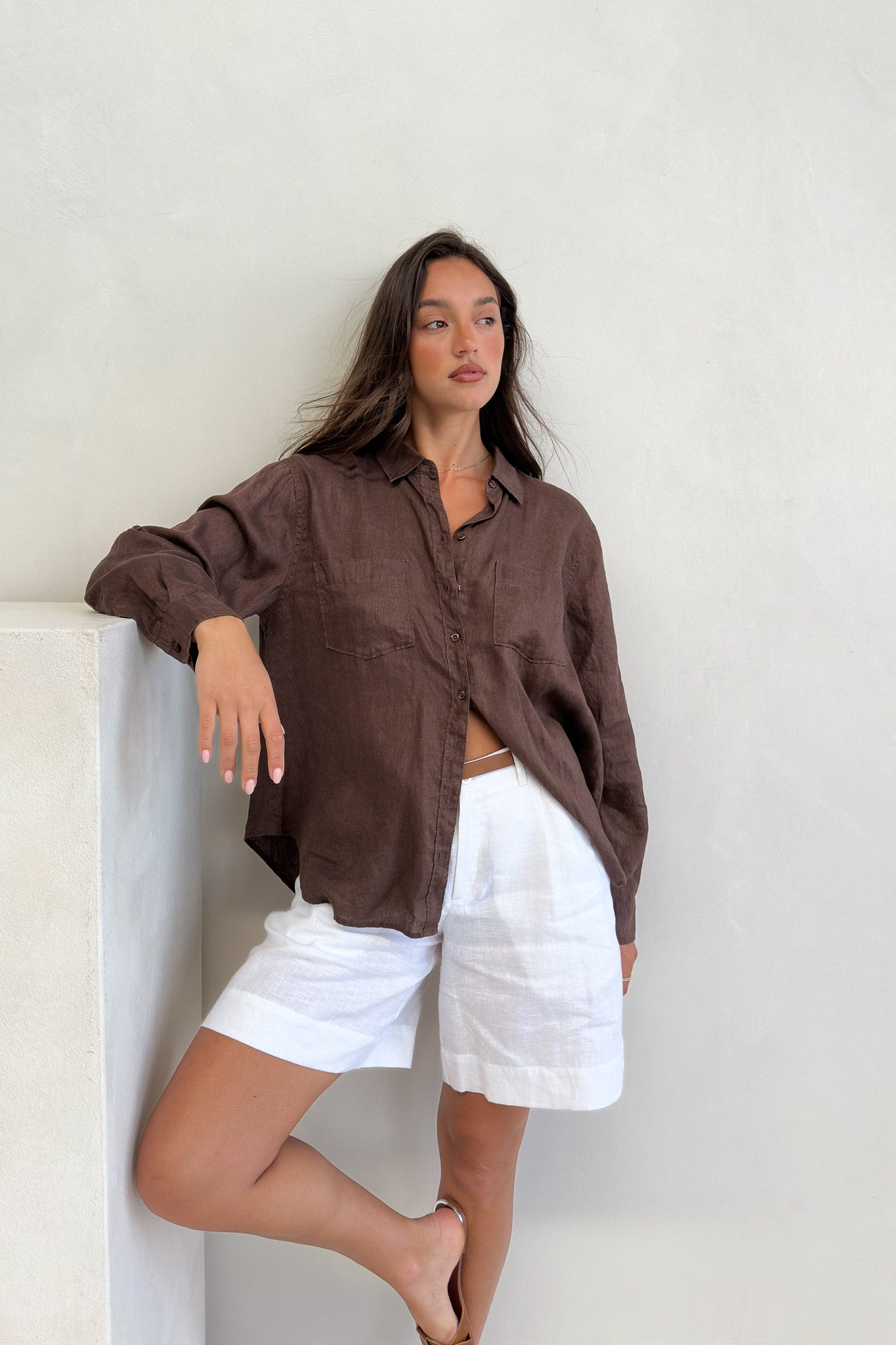 Model wearing Hut Clothing Chocolate Martini Boyfriend Linen Shirt with shirt worn loose with white linen shorts