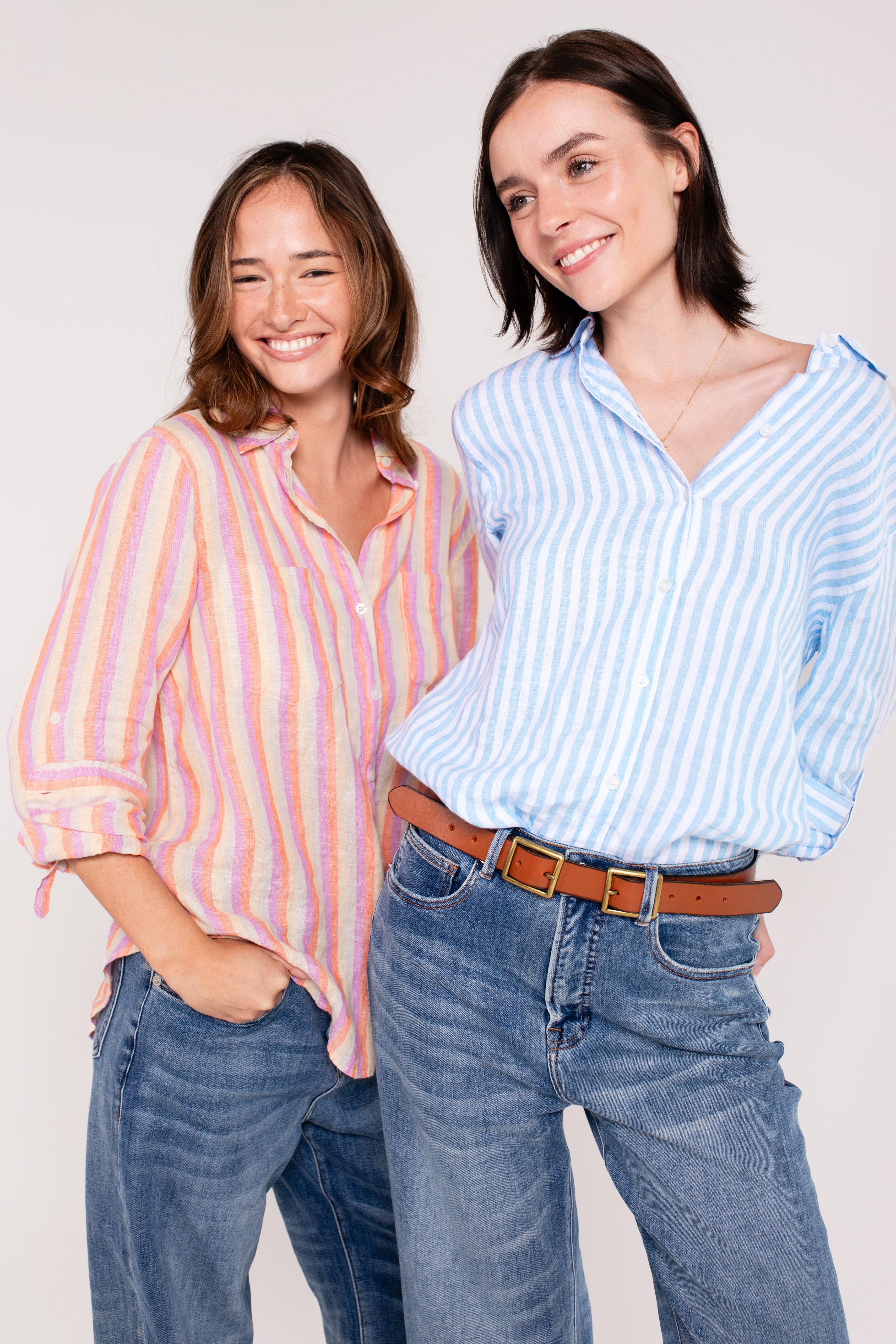 Two models against a white background. One wearing a Hut Clothing groove stripe boyfriend linen shirt and the other wearing a Sky Blue Stripe Boyfriend Linen shirt, both wearing blue denim jeans