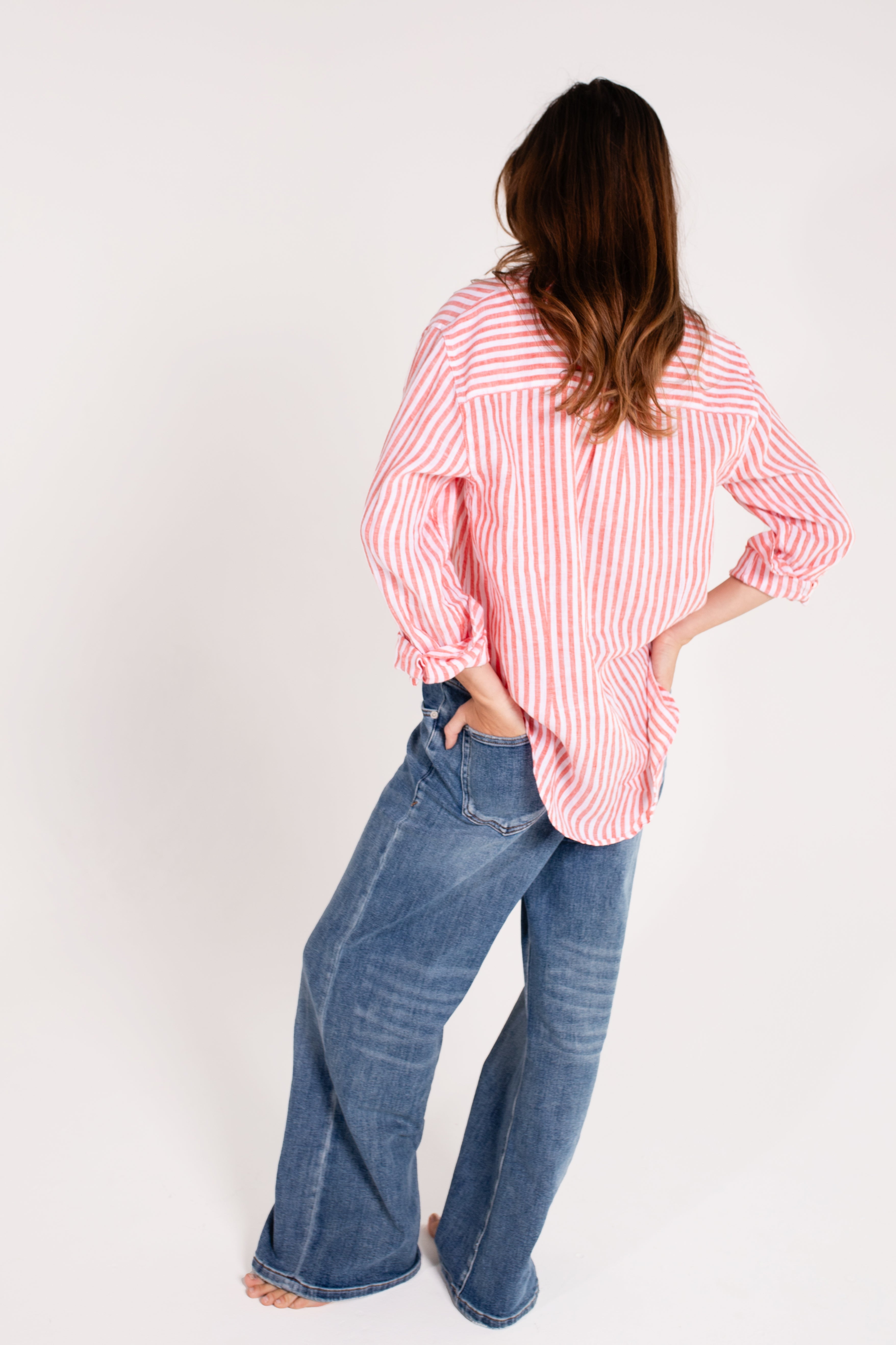 Model wearing a Hut Clothing red and white striped boyfriend linen shirt with long sleeves, paired with blue jeans. The shirt has a relaxed fit and features a scoop hem and tab sleeves