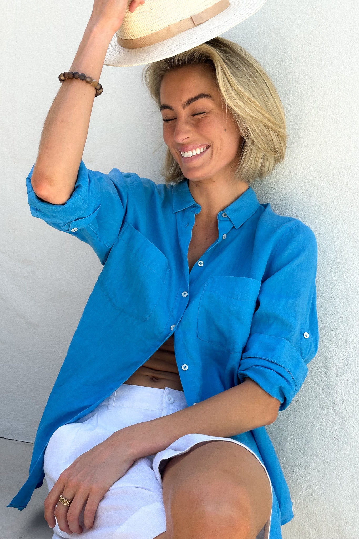 Model smiling wearing Hut Reef Blue Boyfriend Linen Shirt with white linen shorts