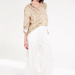 Woman wearing Hut Snake Skin Print Boyfriend Linen Shirt in an oversized fit and rolled sleeves with white trousers and black sandals