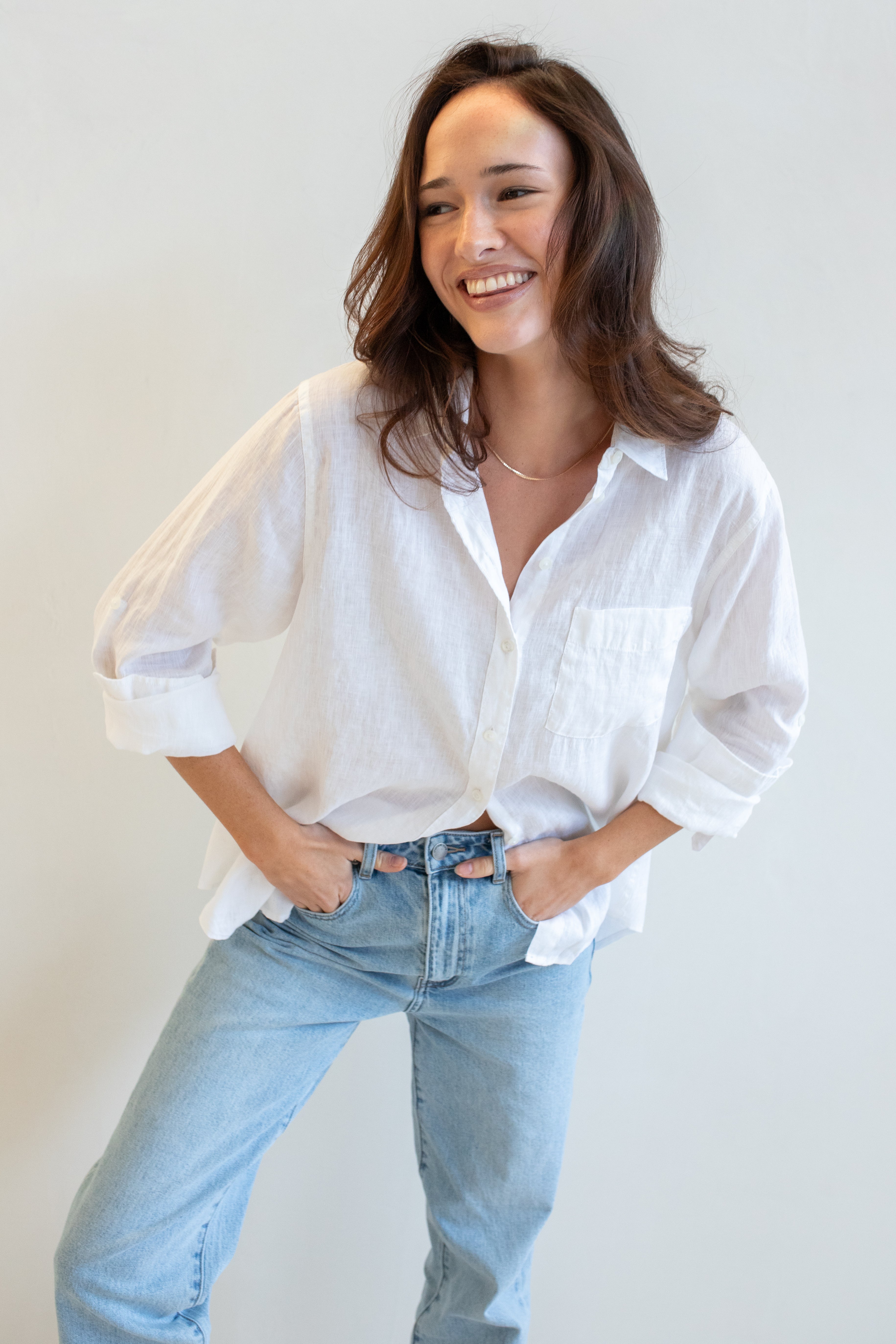 Model wearing a white Hut clothing shirt with one chest pocket and light blue jeans against a plain background, worn oversized fit