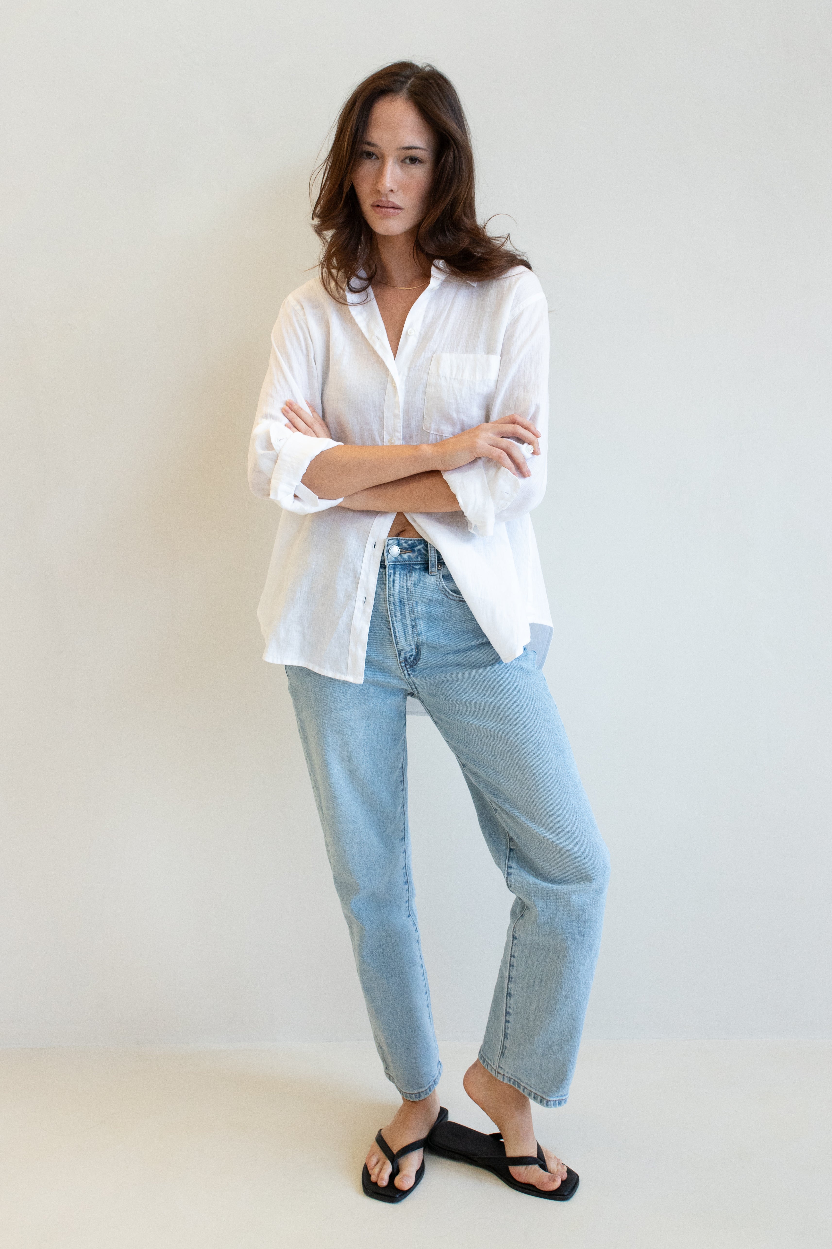 Model wearing a white Hut Clothing shirt with one pocket and light blue jeans against a plain background