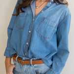 Close up of a Hut blue denim oversized boyfriend shirt and jeans with a neutral background