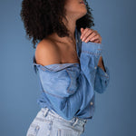 Woman wearing a Hut blue denim shirt and jeans against a blue background