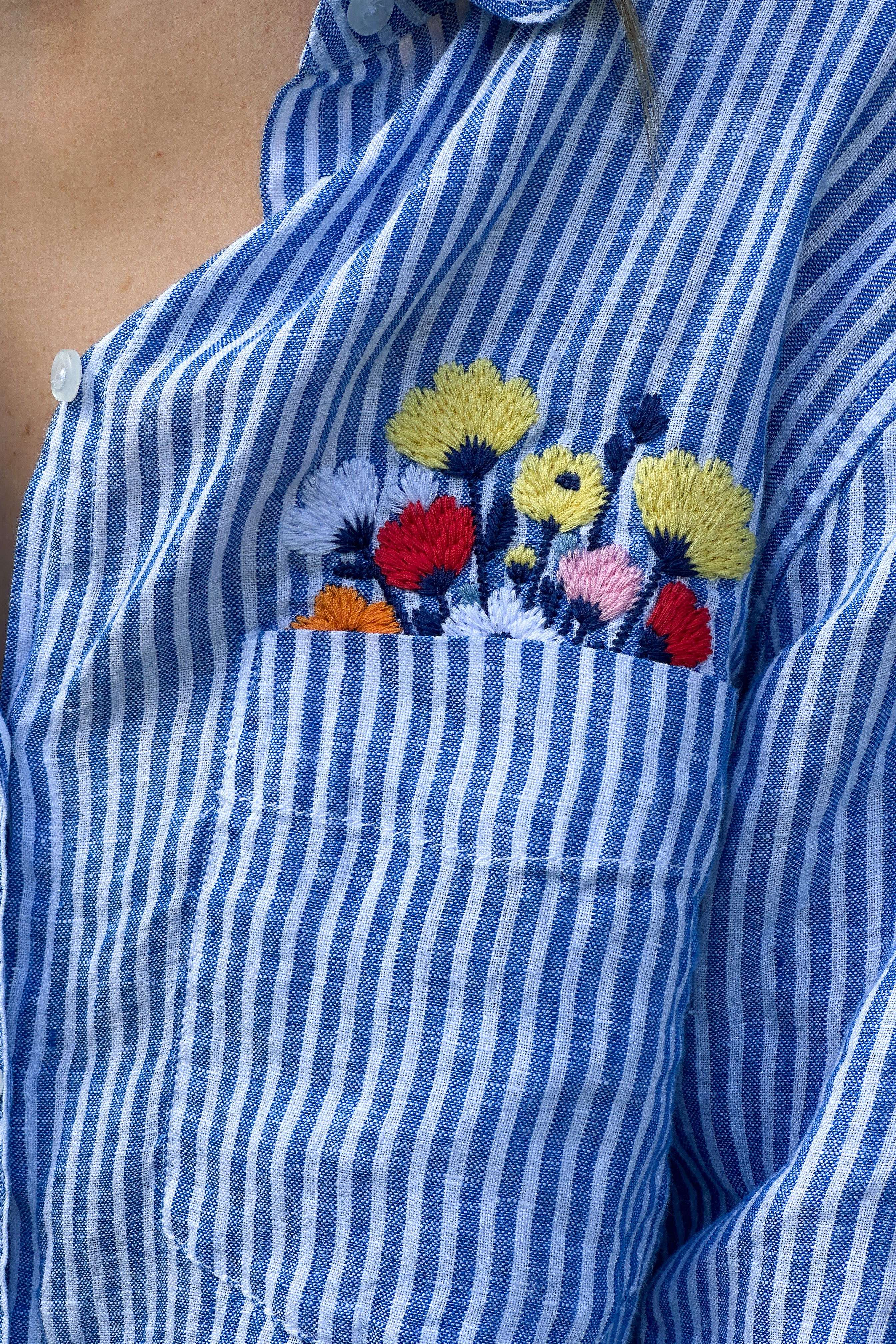 Close up of Flowers In My Pocket blue stripe and floral embroidery boyfriend linen shirt