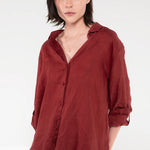 Woman wearing a Hut Burgundy Linen Boyfriend shirt with rolled-up sleeves on a white background