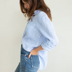 Side profile of Hut Clothing Baby Blue Stripe Boyfriend Linen Shirt with models in hand in back of jean pocket and tab sleeves rolled up