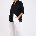 Model wearing a Hut Clothing Black No Pocket Boyfriend Linen Shirt with white linen pants standing against a white background
