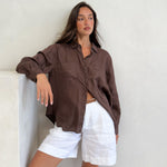 Model wearing Hut Clothing Chocolate Martini Boyfriend Linen Shirt with shirt worn loose with white linen shorts