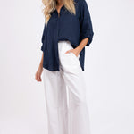 Model wearing Hut Clothing Navy No Pocket Boyfriend Linen Shirt with white wide leg pants 