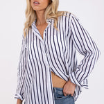 A woman wearing a navy and white striped linen shirt with a collar, button-up front, and long sleeves, paired with blue jeans.