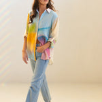 Model wearing a colorful watercolour oversized linen shirt and jeans walking with her hand in jean pocket 
