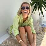 Model laughing sitting down wearing Hut Clothing Shadow Lime Boyfriend Linen Shirt