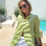 Model sitting with pool in background wearing Hut Clothing Shadow Lime Boyfriend Linen Shirt and white linen shorts