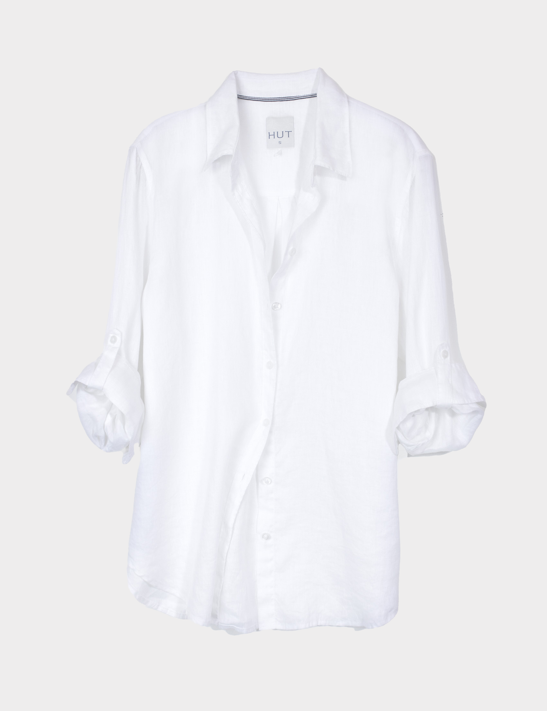 White Boyfriend Linen shirt on a light gray background with no chest pockets and tab sleeves, scooped hem and french seams