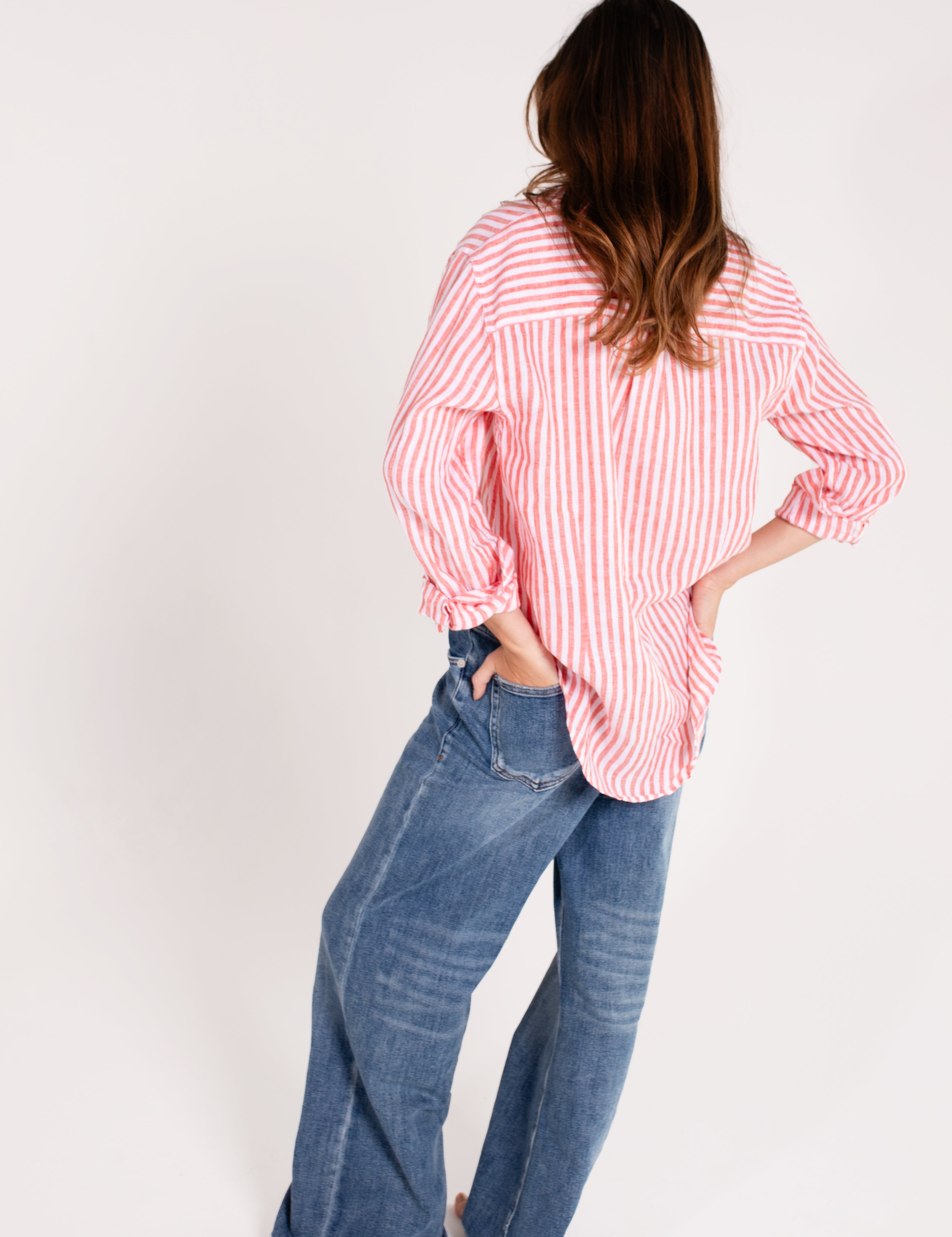 Model wearing a Hut Clothing red and white striped boyfriend linen shirt with long sleeves, paired with blue jeans. The shirt has a relaxed fit and features a scoop hem and tab sleeves