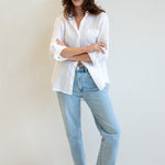 Model wearing a white Hut Clothing shirt with one pocket and light blue jeans against a plain background